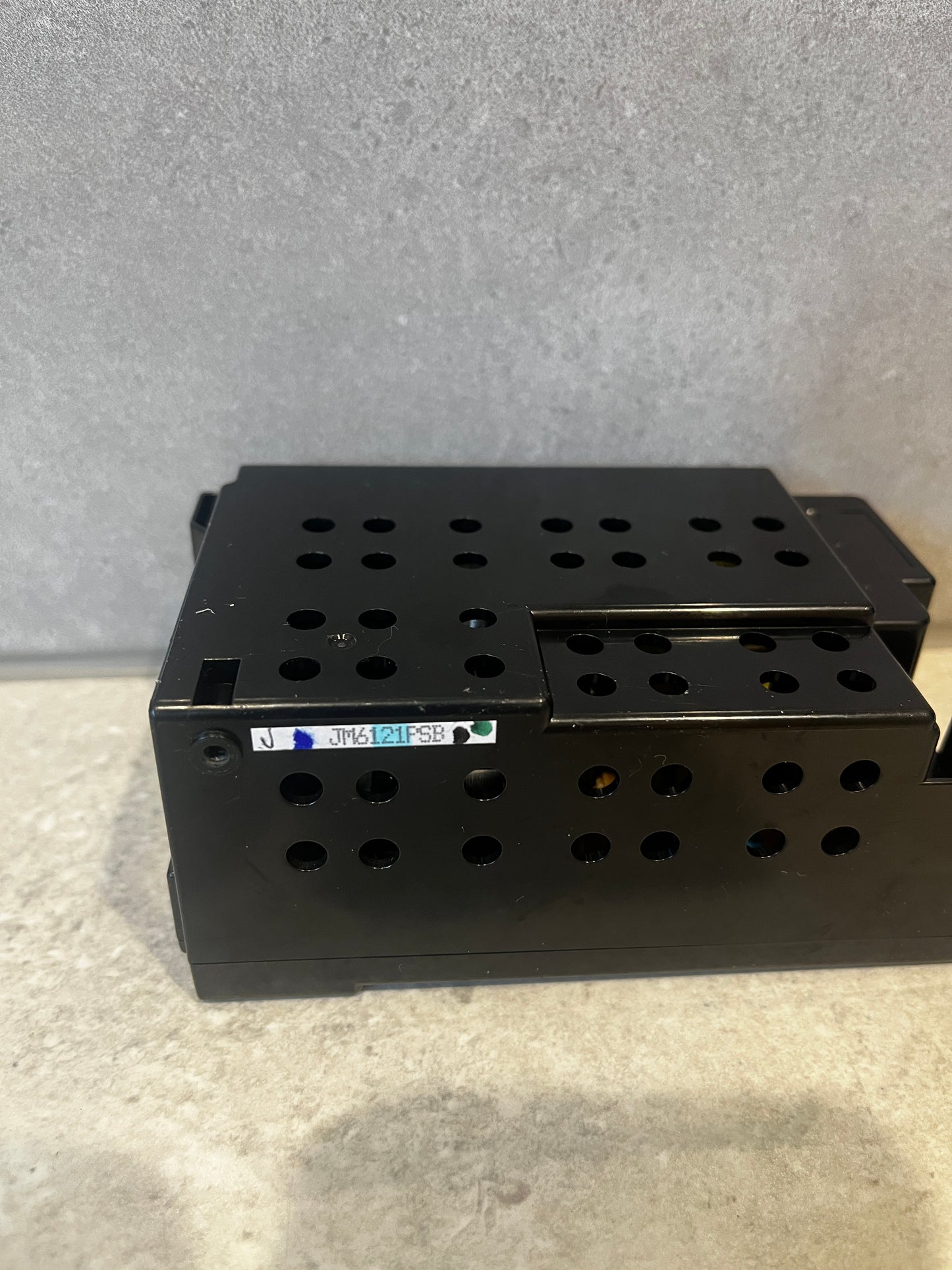 Close-up of black metal power supply showing ventilation holes and sticker label
