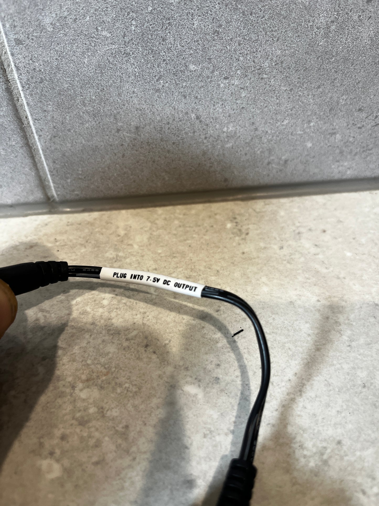 Detail of cable label stating 'PLUG INTO 7.5V DC OUTPUT' on adapter cable