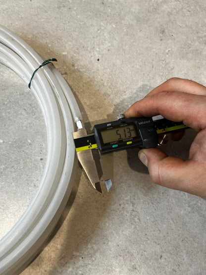 Person measuring outer diameter of silicone tubing with caliper