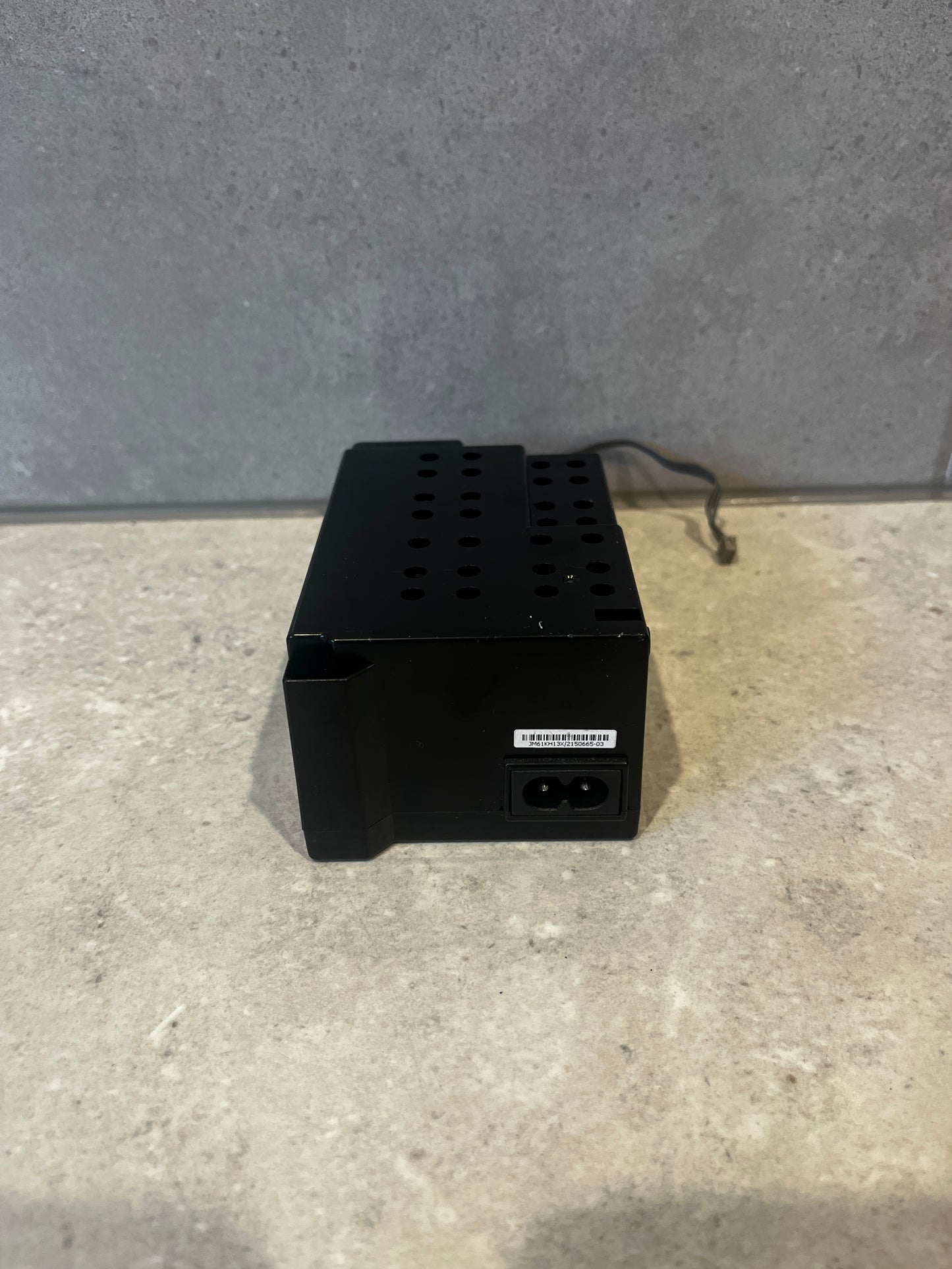 Back view of black metal power supply unit showing power input connector and label