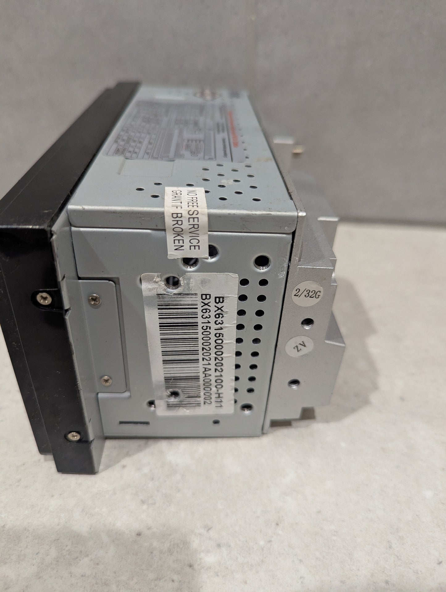 Side view of car stereo head unit showing barcode and service sticker