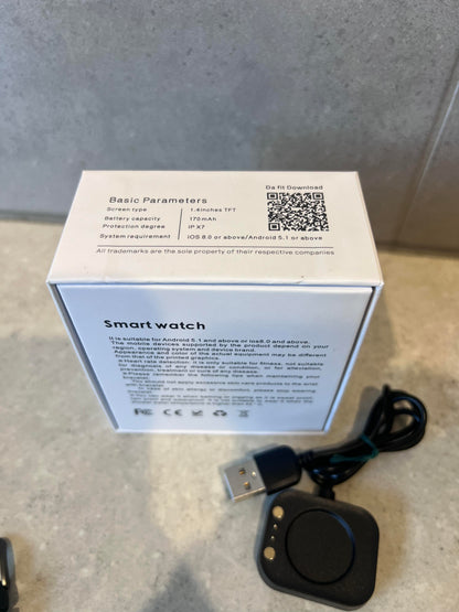 Back of smart watch box showing specifications and charging base with cable
