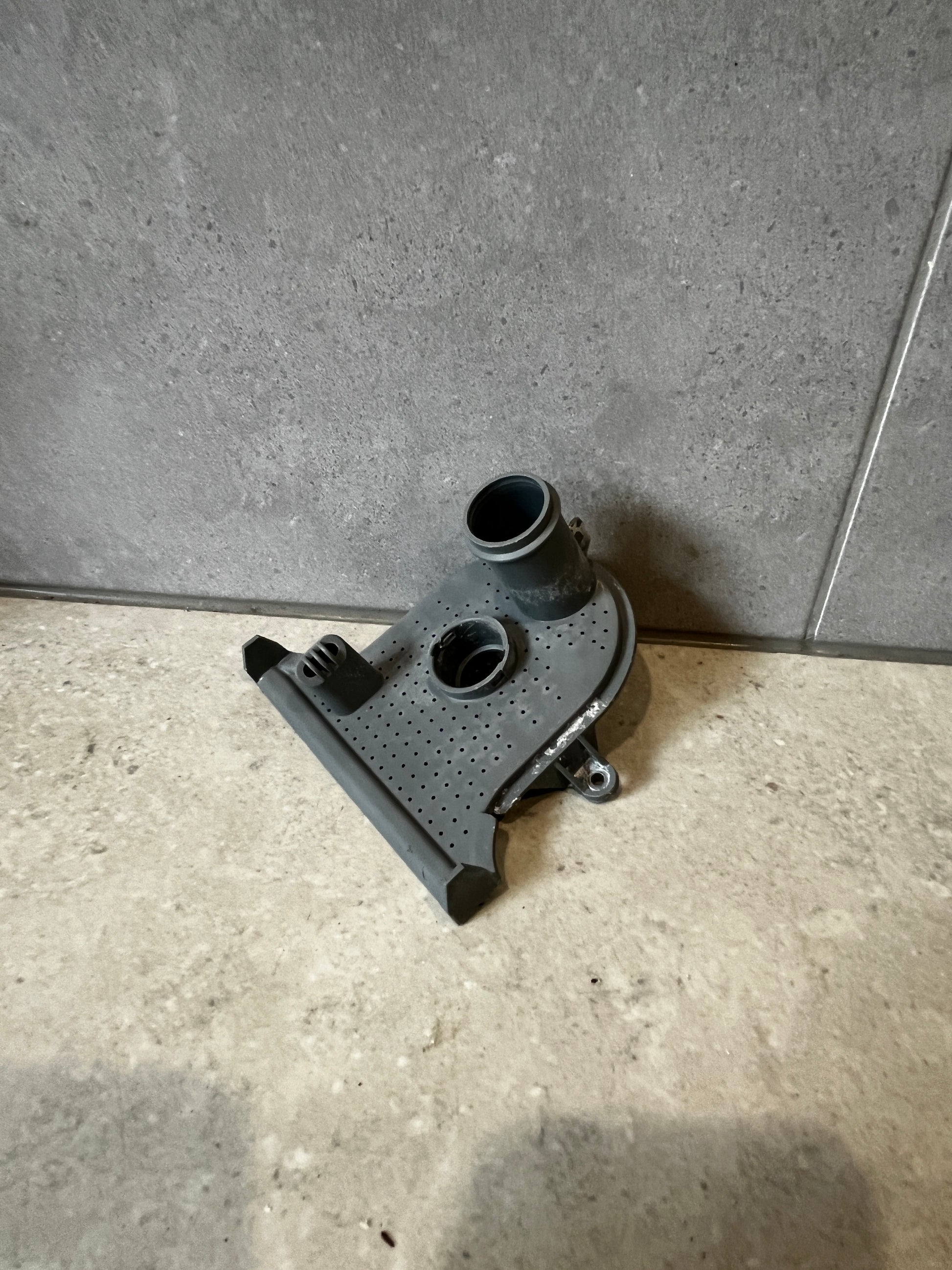 Top angle of gray plastic washer pump housing part showing port and mounting features