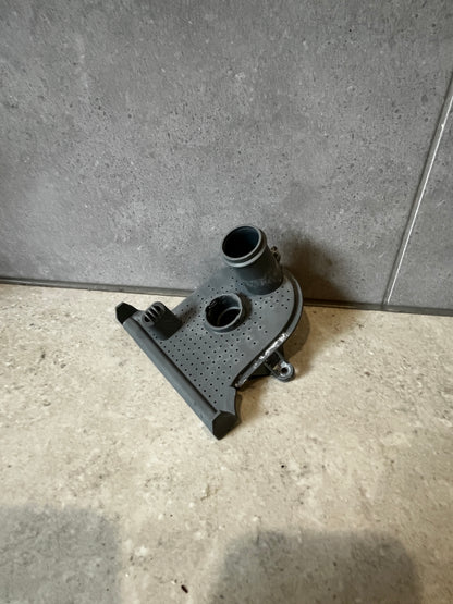 Top angle of gray plastic washer pump housing part showing port and mounting features