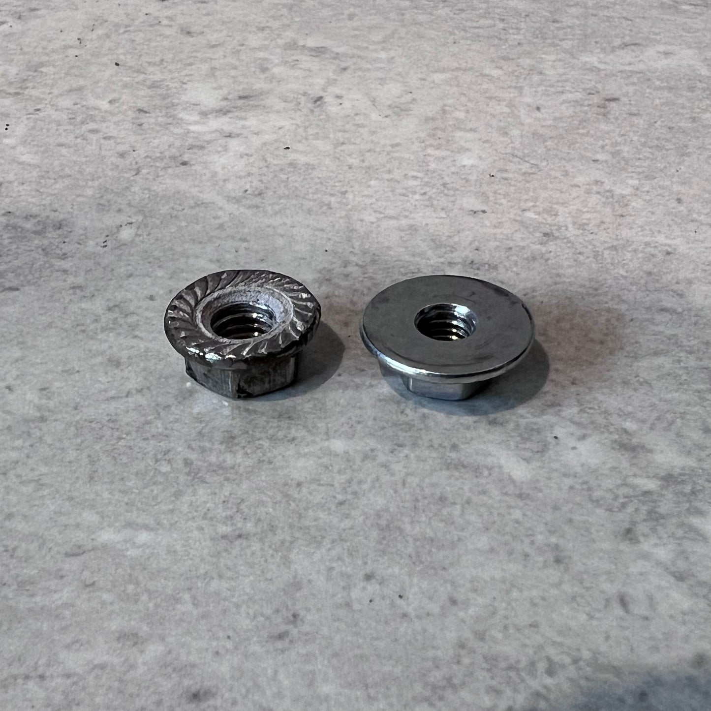 Bottom view of two metal flange nuts showing serrated and smooth flanges