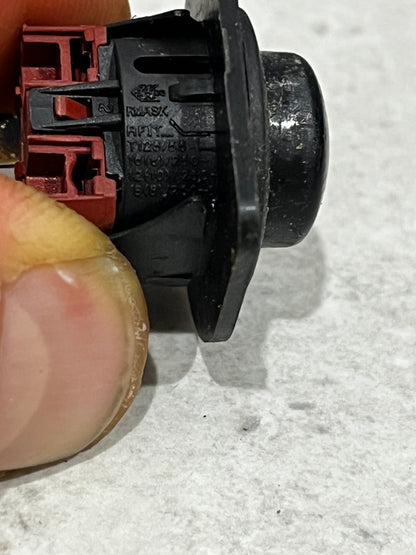 Close-up side view of black round rocker switch with manufacturing markings