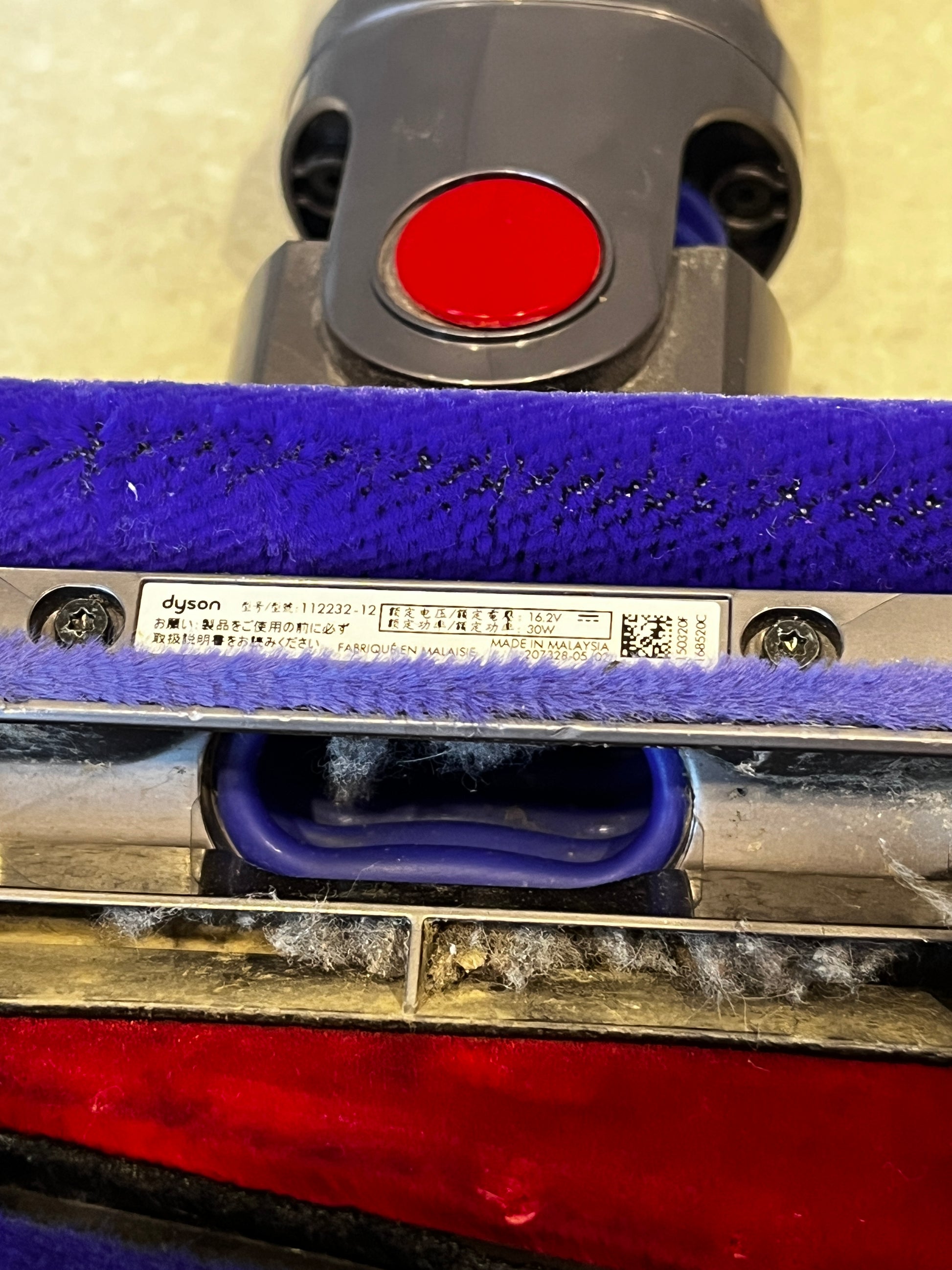 Close-up of Dyson vacuum brush head label and fabric roller with dust