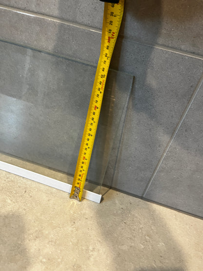 Close-up of clear safety glass panel with measuring tape showing height