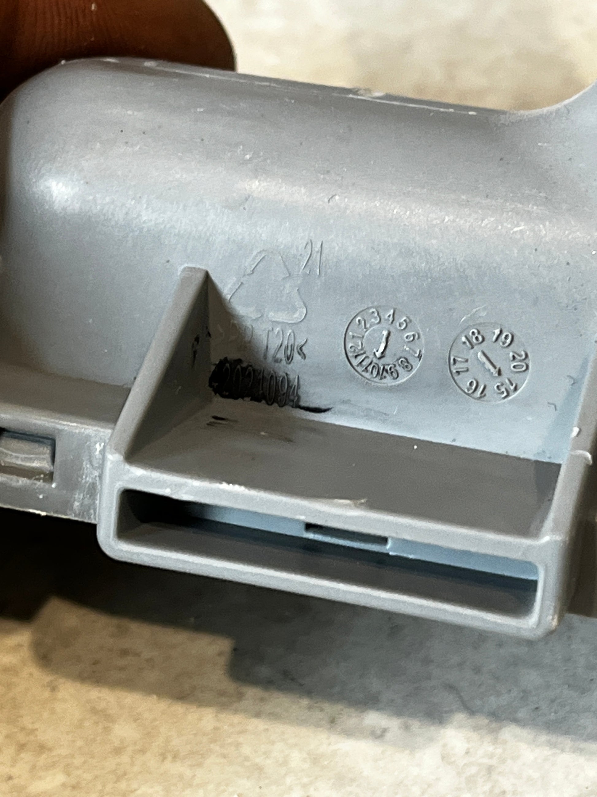 Close-up of markings and recycling symbol on dishwasher spray arm support