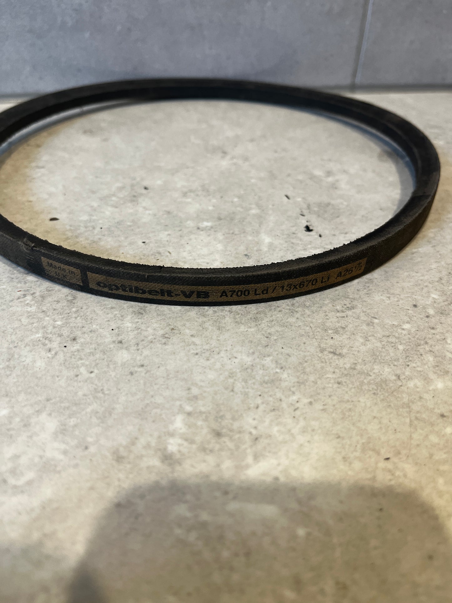 Close-up of a single industrial V-belt showing Optibelt labeling on a light counter