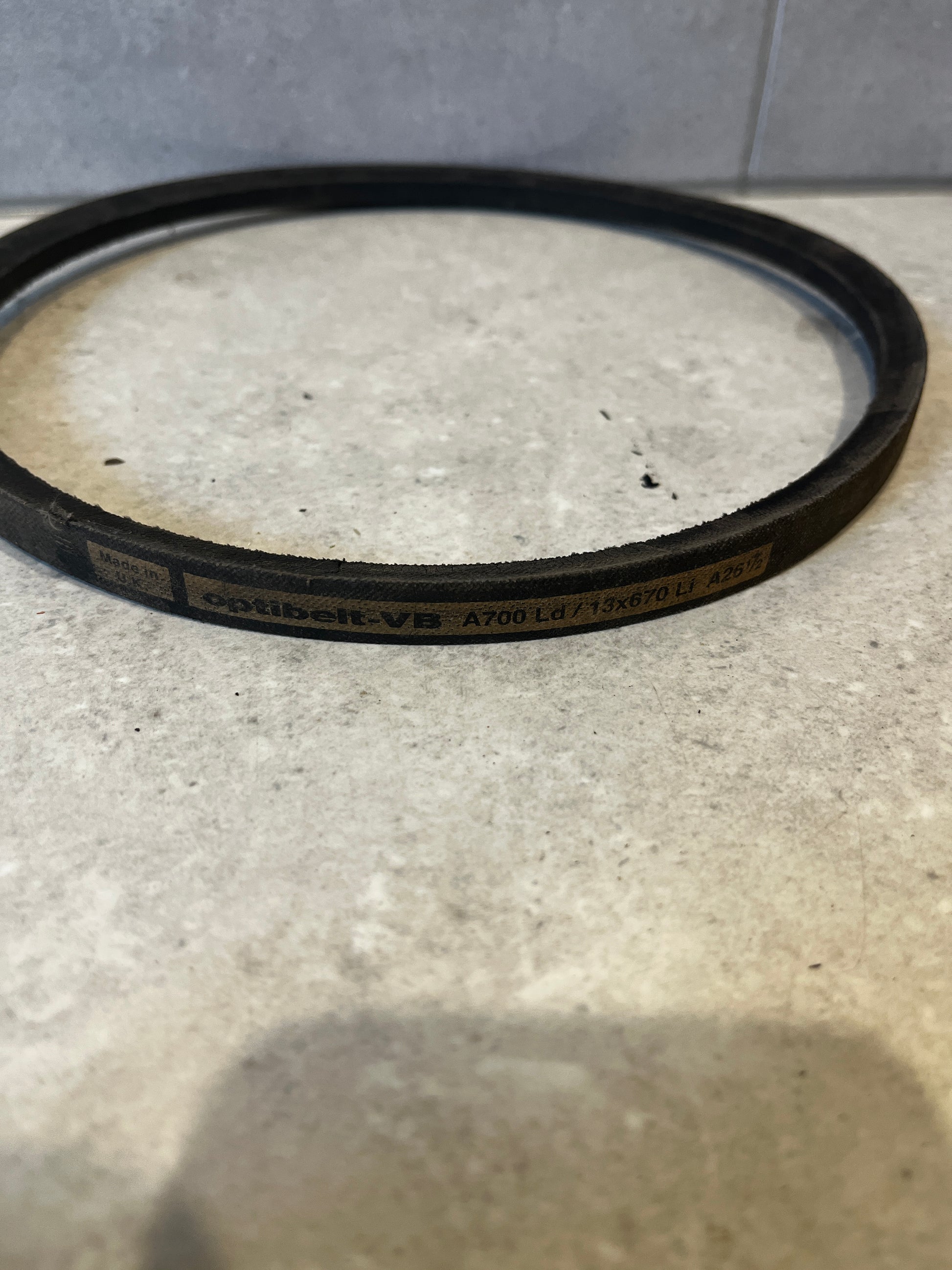 Close-up of a single industrial V-belt showing Optibelt labeling on a light counter