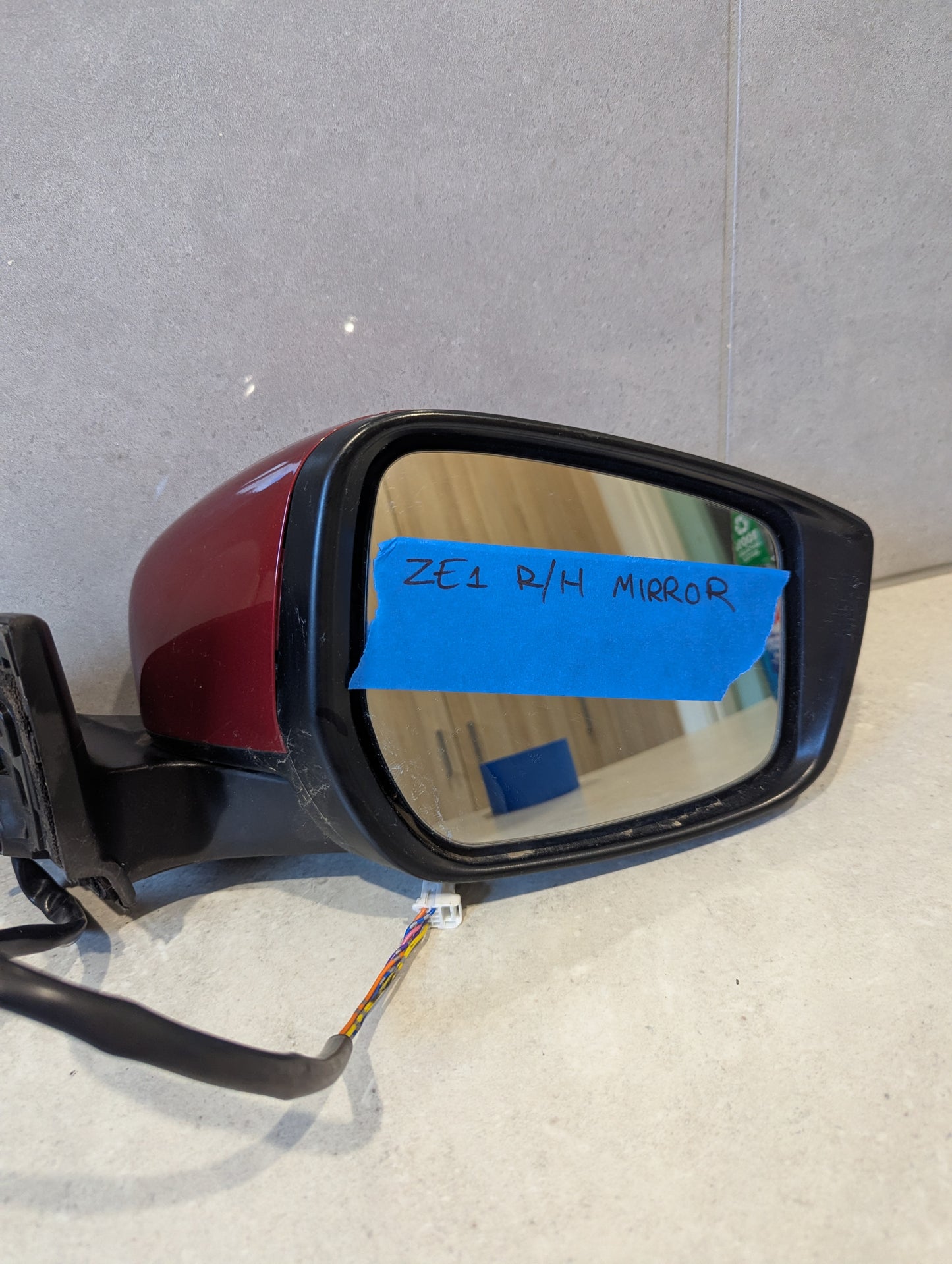 Front view of mirror glass with blue tape labeled 'ZE1 R/H MIRROR' and attached wiring