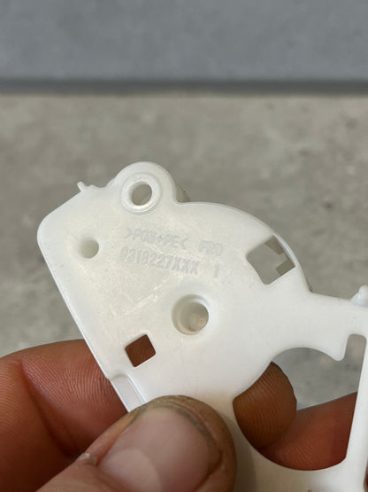 Close-up of manufacturer's markings and material codes on white plastic lever bracket