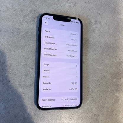 Screen close-up showing iPhone 13 Mini About page with 128GB capacity and iOS version 16.4.2