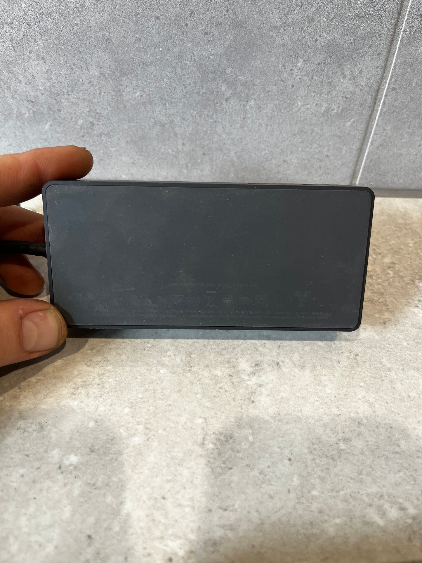 Hand holding a Microsoft Surface power adapter
