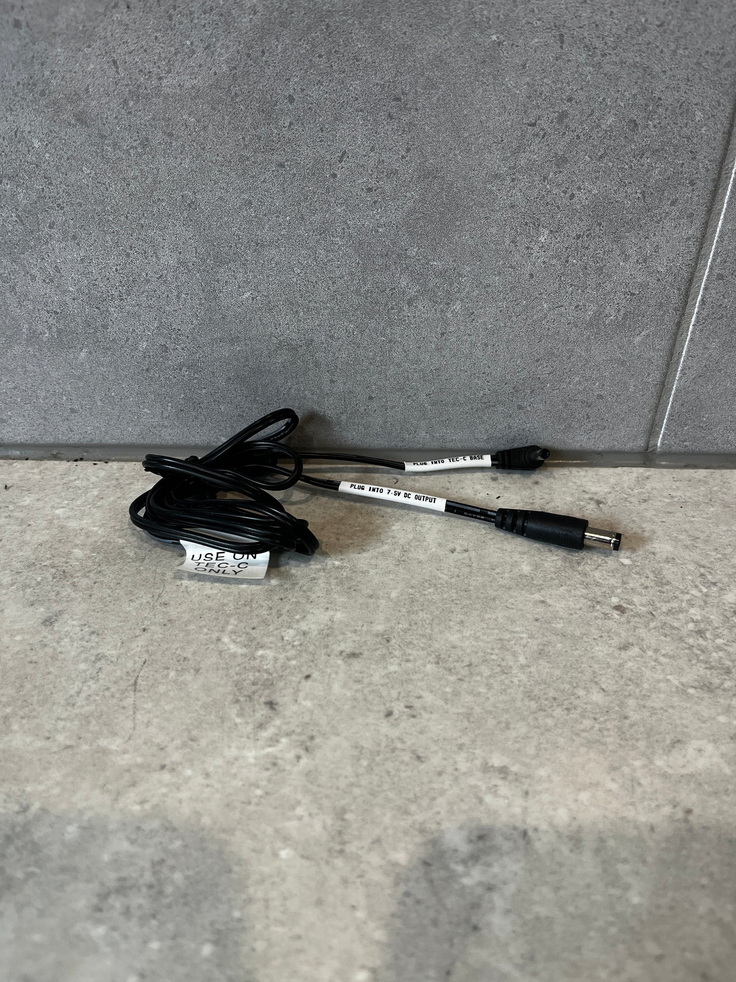 TEC-C base adapter cable coiled on surface, showing both connectors and labels