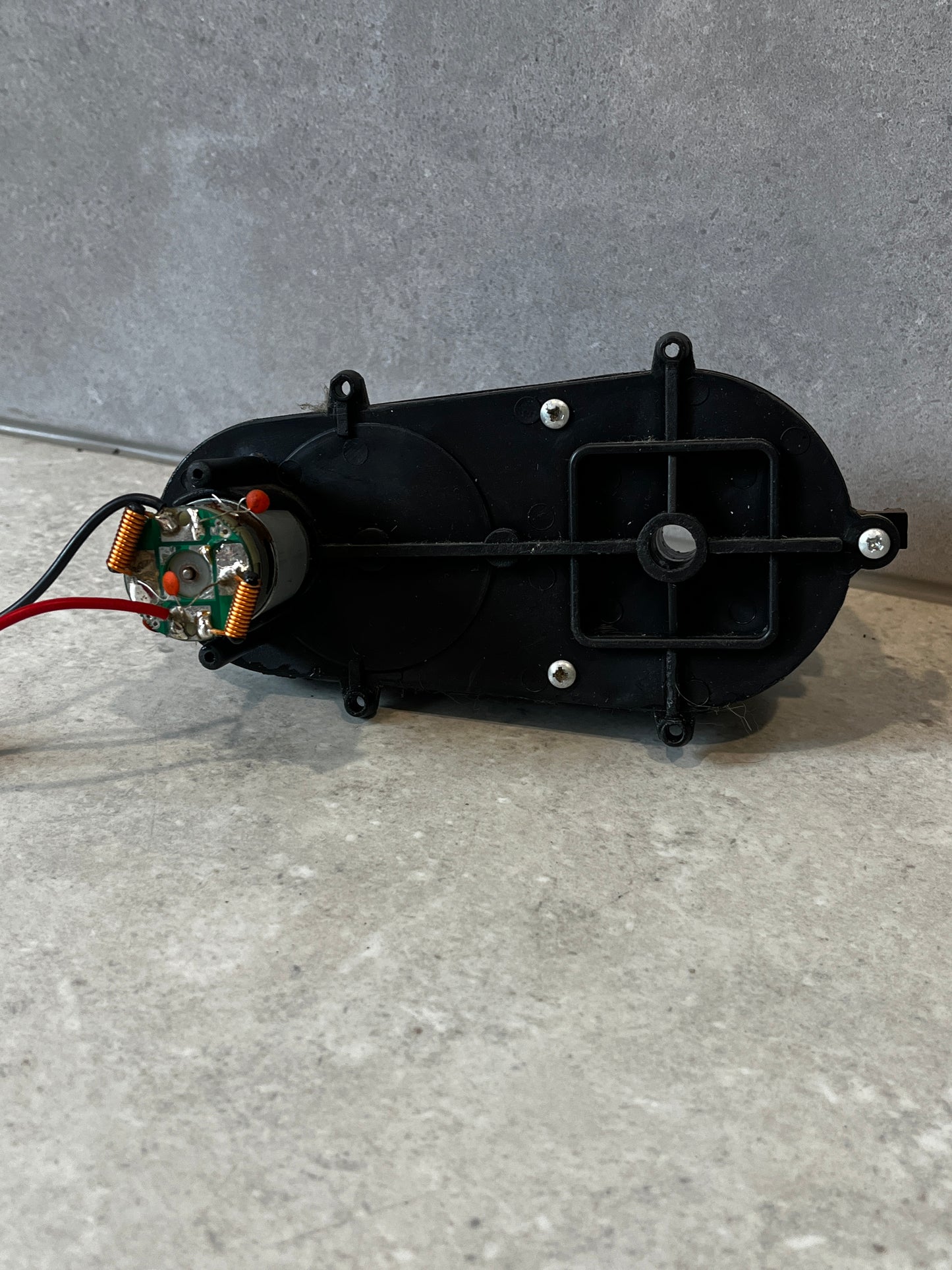 Rear view of black plastic gearbox housing with screws and wiring