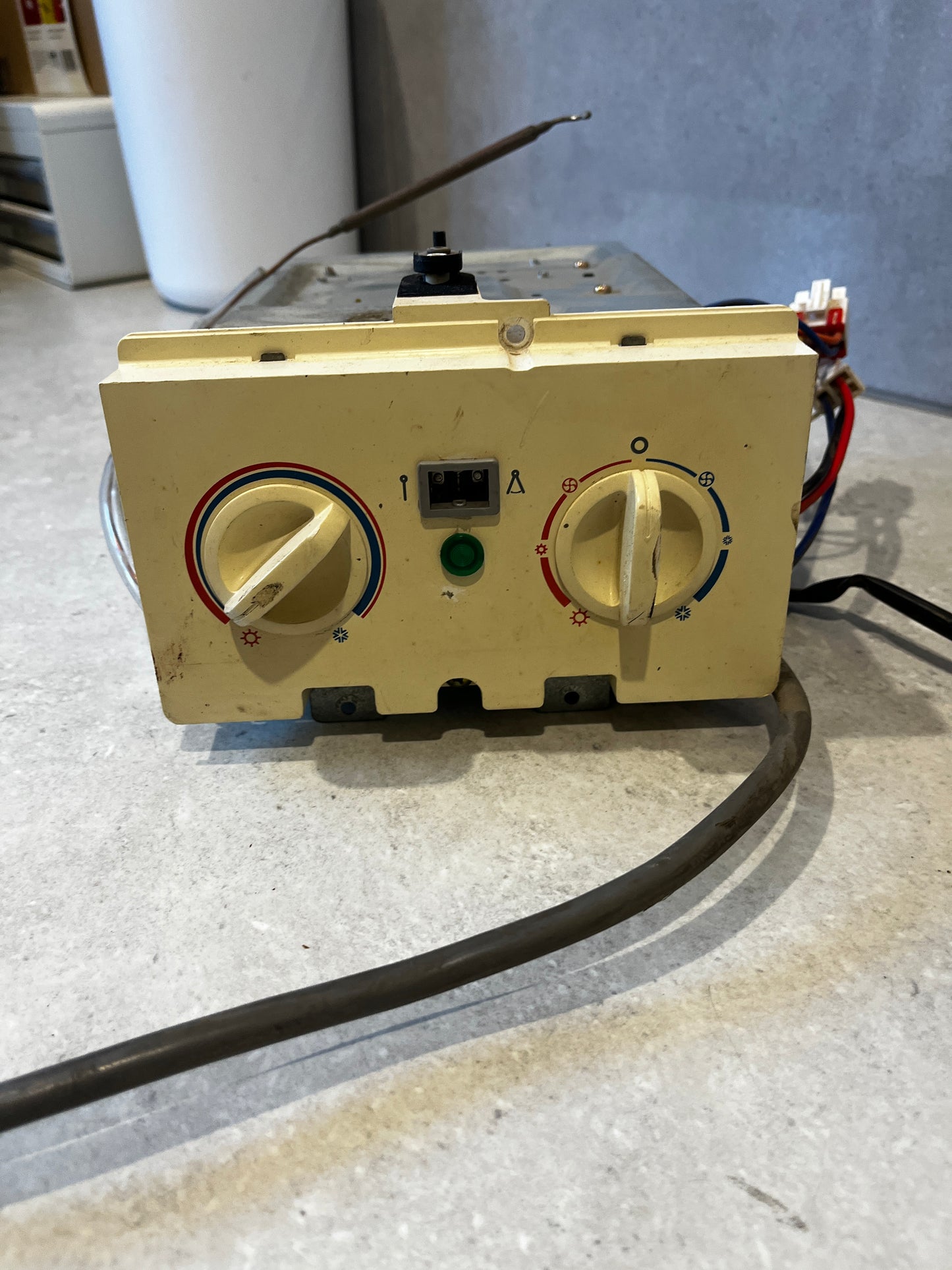Front view of thermostat control panel with temperature and fan control knobs