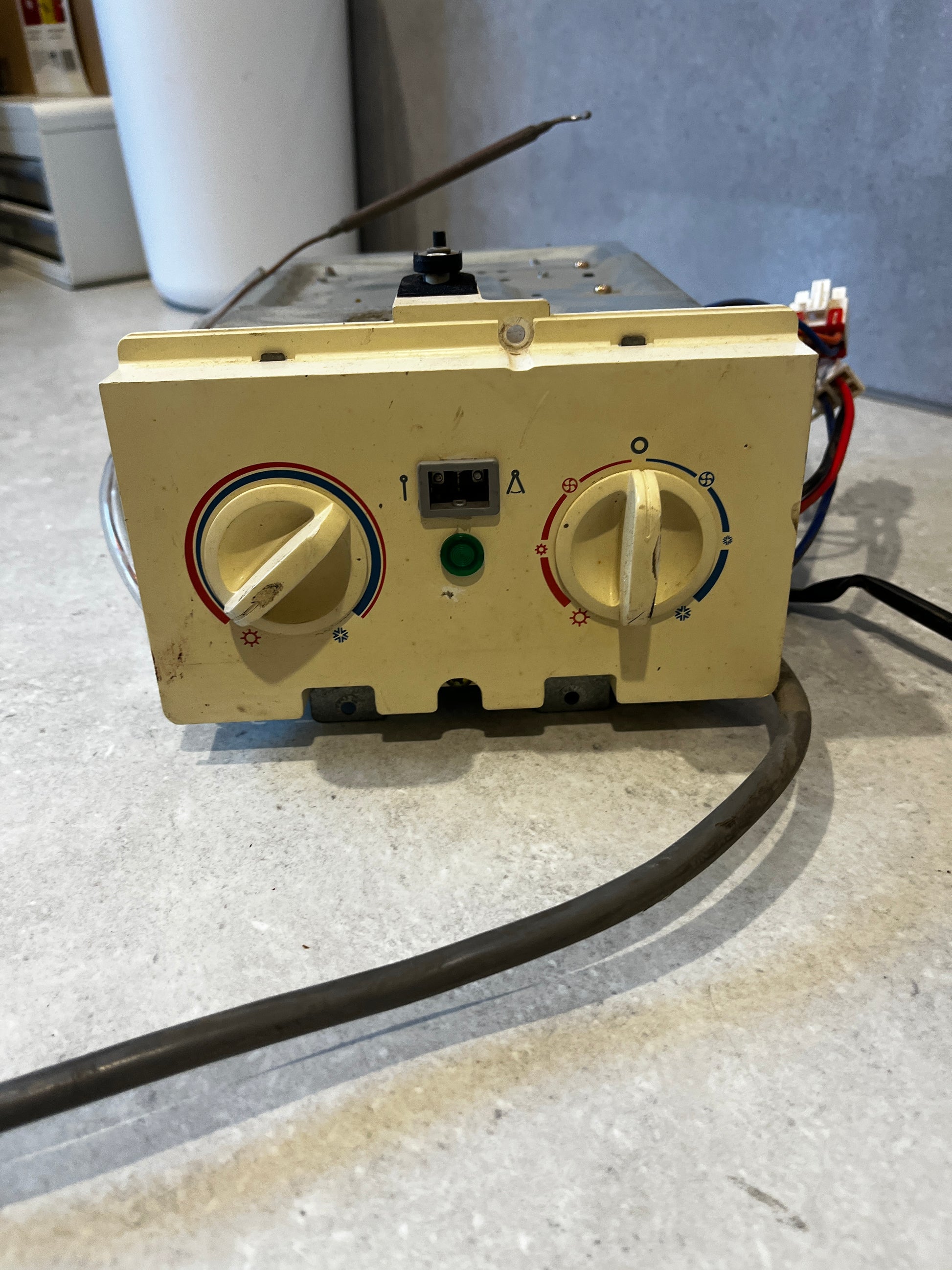 Front view of thermostat control panel with temperature and fan control knobs