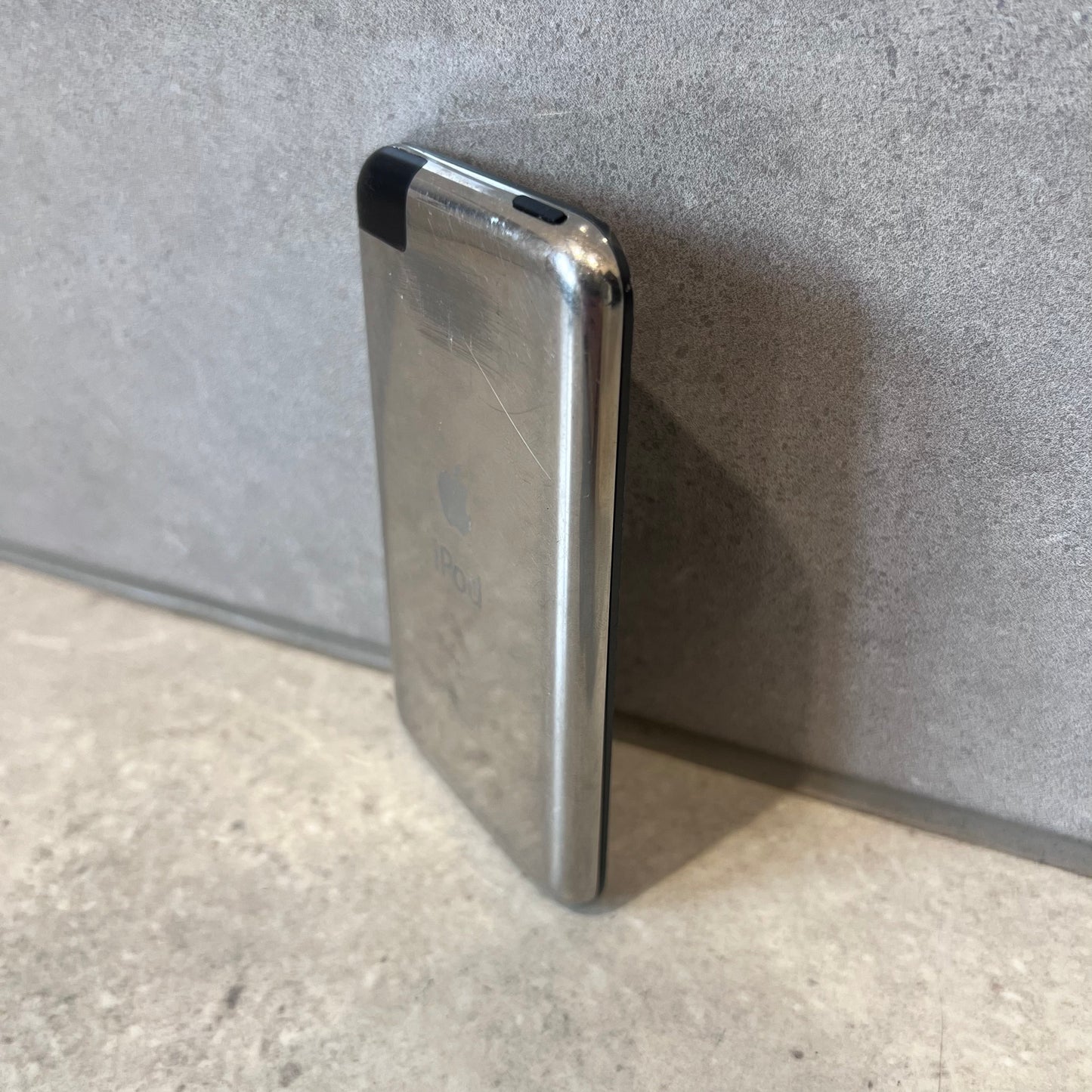 Side view of scratched Apple iPod Touch showing metal back and black plastic corner
