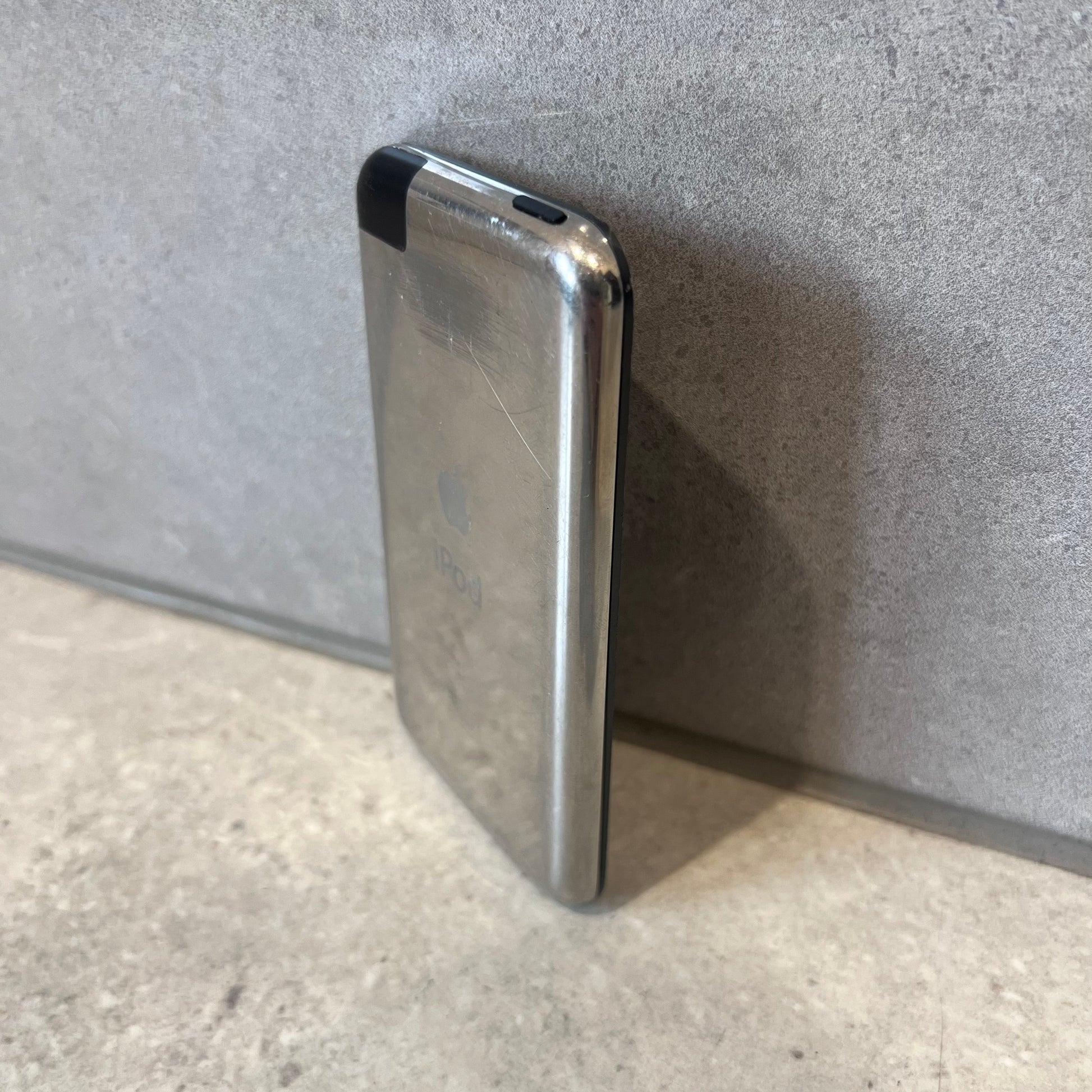 Side view of scratched Apple iPod Touch showing metal back and black plastic corner