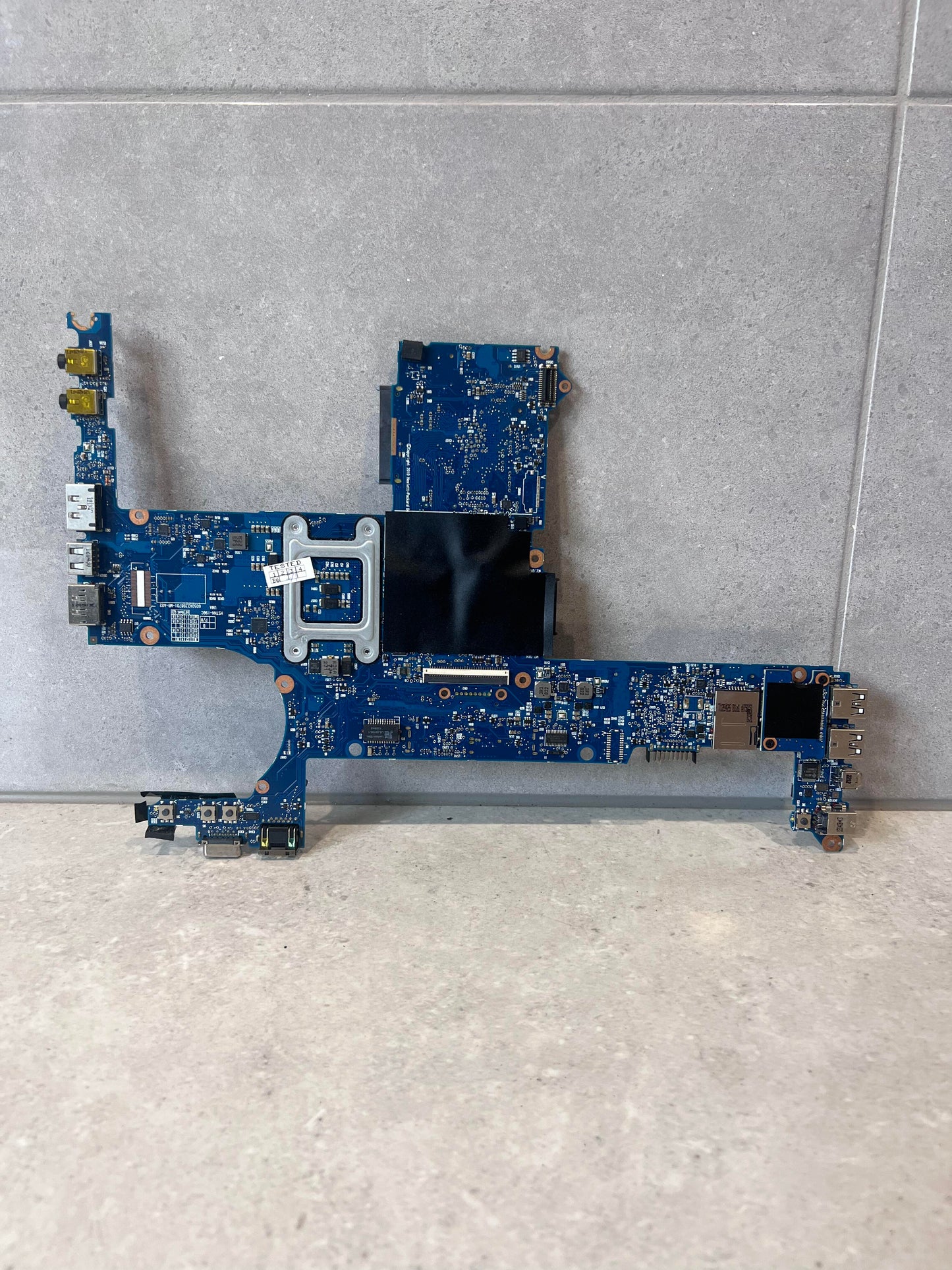 Back view of blue laptop mainboard, showing circuitry and connectors