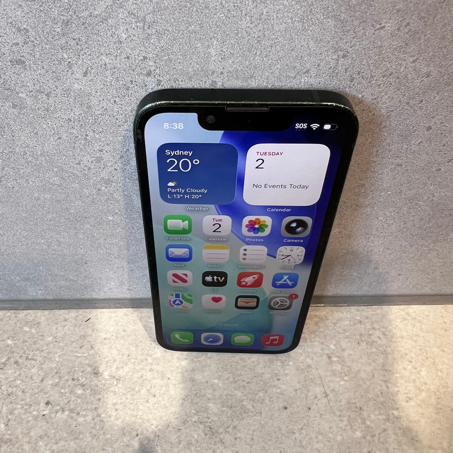 Bottom view of iPhone 13 Mini showing charging port and speaker holes with noticeable wear on edges