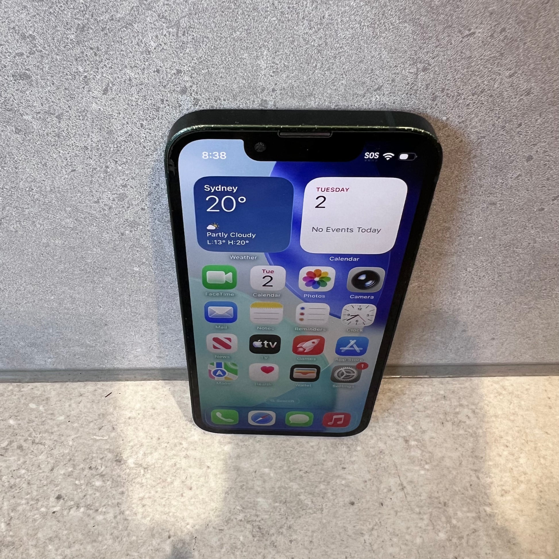 Bottom view of iPhone 13 Mini showing charging port and speaker holes with noticeable wear on edges